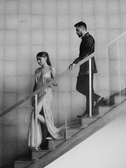 A candid black and white shot of the couple on a staircase. Their relaxed interaction and the architectural lines create a modern and effortlessly cool portrait.