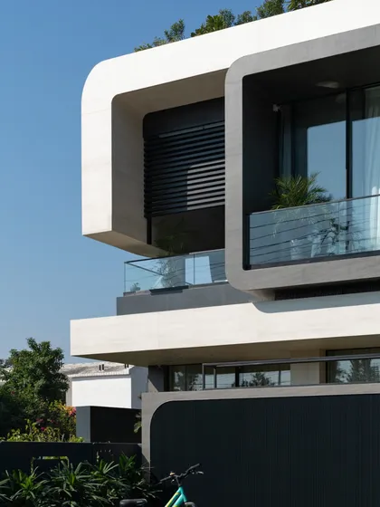 A close-up of the facade of Residence 100, detailing the clean lines, recessed windows, and glass balcony that contribute to its modern aesthetic.