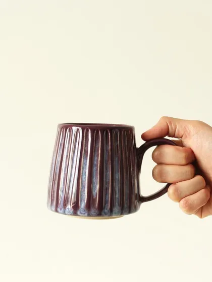There's nothing like a favorite mug for your morning coffee. This 'Aubergine Drip' mug, with its deep, iridescent glaze and hand-scooped texture, is designed to fit perfectly in your hands and brighten your day.