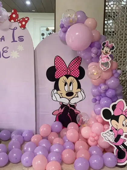 A detailed shot of the Minnie Mouse backdrop, focusing on the character cutout and the purple and pink balloon garland.