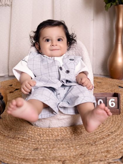 Celebrating a six-month milestone with a classic studio portrait. The baby is dressed in a smart vest and shorts, with a calendar block marking the special half-birthday.