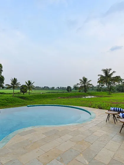 The infinity pool at Fireflies Resort overlooks the serene Kabini river and surrounding paddy fields. The pool's edge is designed to disappear, creating the illusion of the water extending directly into the natural landscape.