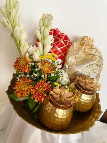 A close-up of the hammered brass jars and brocade potlis inside the festive urli hamper.