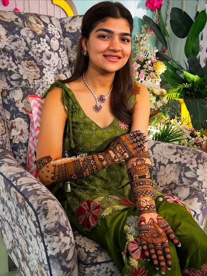 A happy bride proudly displaying her full-arm mehandi for the camera.