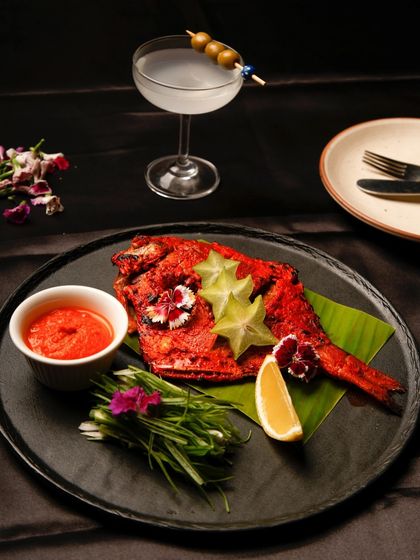 A fiery tandoori fish, beautifully plated with starfruit and edible flowers. My menu has something for everyone, including delicious Indian-style grilled options.