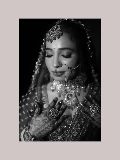 A timeless black and white bridal portrait. This shot emphasizes the bride's serene expression and the intricate details of her jewelry and henna-adorned hands.