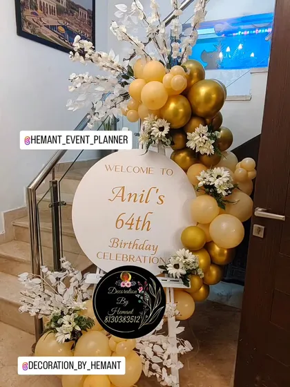 An elegant welcome board for a 64th birthday celebration. The custom round sign is framed by a beautiful arrangement of gold and pastel yellow balloons, accented with white artificial flowers for a classy first impression.
