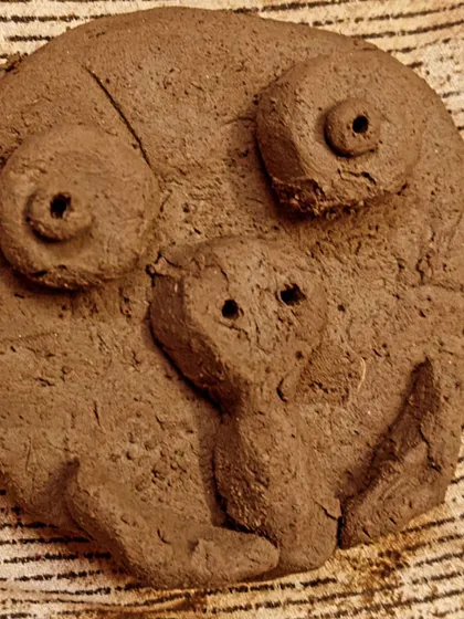 A whimsical face sculpted from natural clay. When children are given the freedom to create, their unique personalities and sense of humor shine through in their work.
