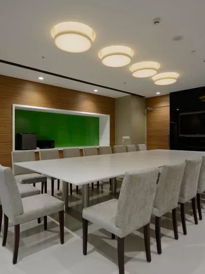 An executive dining room that can also function as a meeting space. The design is clean and modern, with wood-paneled walls and a large, simple table.