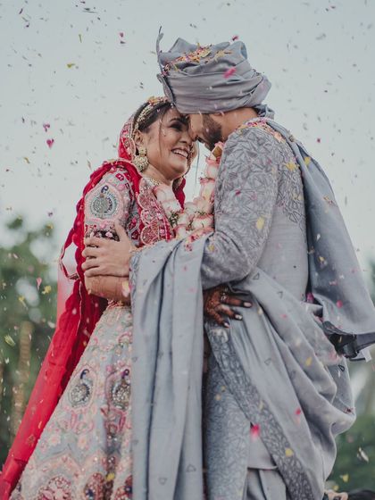 A joyful, candid embrace between the couple, surrounded by a shower of petals. Their laughter is infectious and makes for a beautiful memory.