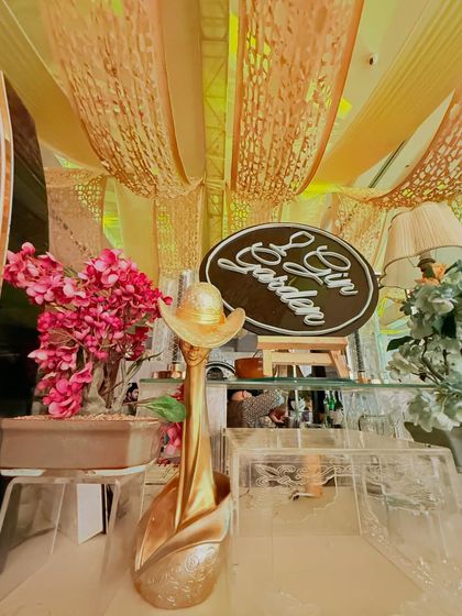 A charming 'Gin Garden' sign on an easel, part of a beautifully decorated station with floral and artistic elements.