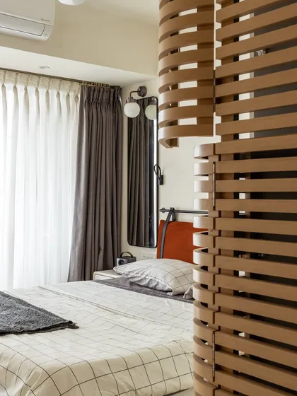 The custom wooden slat partition in the bedroom is a key feature of the design. It allows light to filter through while providing a sense of privacy.