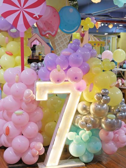 A close-up of the light-up marquee number '7' surrounded by candy and ice cream-themed balloon sculptures. These details make our Candyland theme extra sweet.