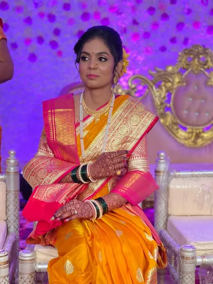 A beautiful bride seated during her wedding ceremony. Her yellow and pink Paithani saree is a classic choice, complemented by soft, elegant makeup.
