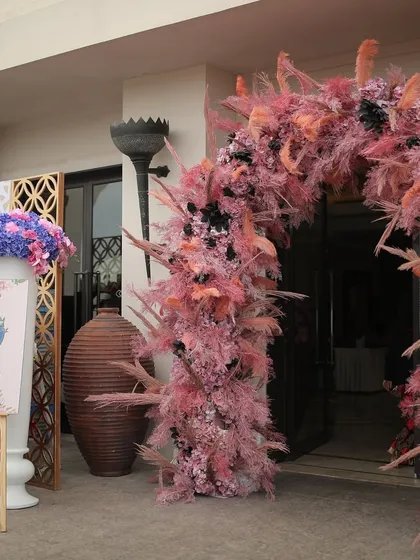 A dramatic pink pampas grass archway welcomes guests to a beachside event in Bahrain, demonstrating our flair for creating modern, impactful decor in any location.