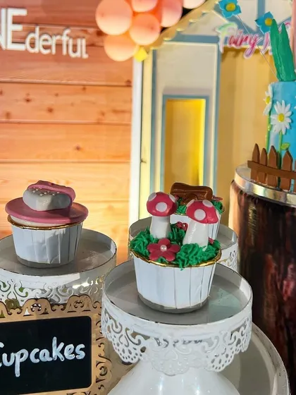 Themed cupcakes for the enchanted forest party, with intricate designs like mushrooms and hearts, displayed on elegant stands.