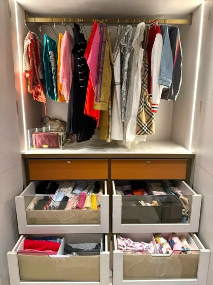 This wardrobe section features multiple drawers with glass fronts, revealing perfectly organized contents. This design combines the clean look of closed storage with the practical benefit of being able to see what's inside.
