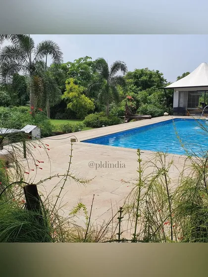 This backyard was transformed into a private resort with a large swimming pool and a cabana. The landscape is filled with tropical plants and palms, providing a sense of escape and luxury.