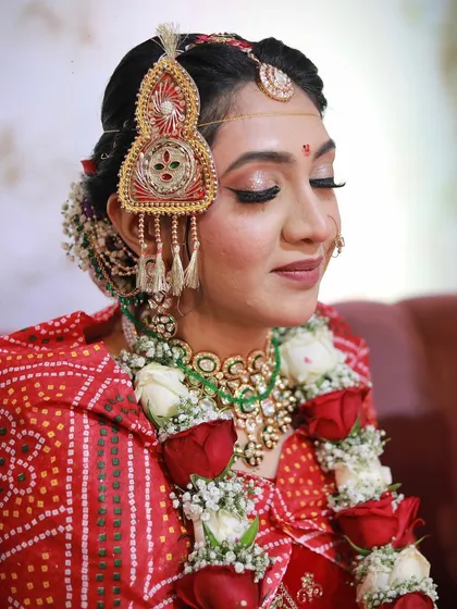 A close-up on the traditional Rajasthani borla and the soft, shimmery eye makeup that complements the red bandhani outfit.