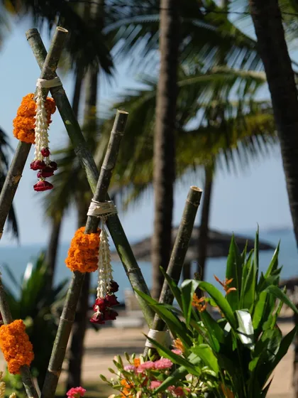 A minimalist detail from the beachside Haldi, with marigold and tuberose garlands tied to a bamboo frame against the backdrop of the sea.
