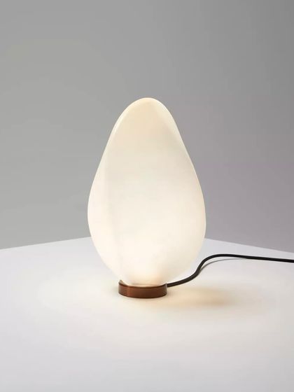 The white glass Solace lamp, with its warm, inviting glow, is perfect for creating a cozy and serene ambiance on a side table or shelf.