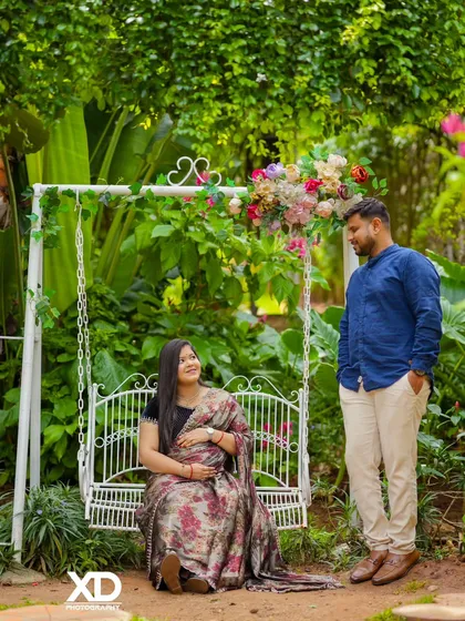 A sweet moment between a couple on a garden swing, surrounded by lush greenery.