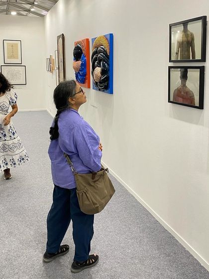 A visitor looking closely at the sculptural paintings of G. Ravinder Reddy.