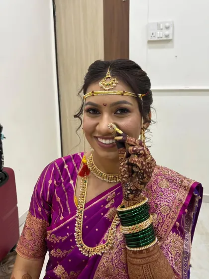 The delicate details make all the difference in a traditional Maharashtrian bridal look. Here, I'm adjusting the classic Maharashtrian nath, ensuring it sits perfectly. Her makeup is kept soft and radiant to complement the rich purple saree and gold jewelry.