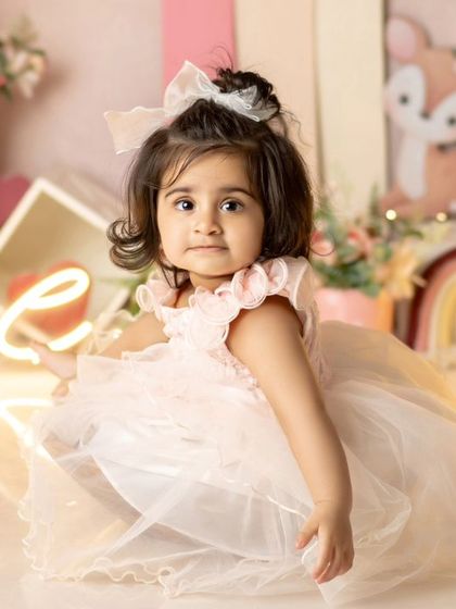 A pretty princess in her beautiful pink dress, surrounded by glowing "ONE" lights. A magical setup for a magical milestone.