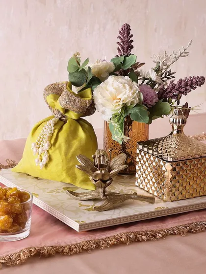 The Sunlit Festive hamper is designed to infuse your Diwali with a golden glow. It includes a candle holder, a metal jar with cookies, a flower vase, and a potli of golden berries.