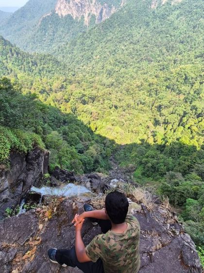 A trekker looking down at the magnificent Koodluthirtha Falls from a viewpoint above.
