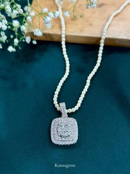 This necklace, featuring a brilliant diamond cluster pendant on a string of white pearls, is designed to be a modern heirloom. It is a piece of history that shines through time.