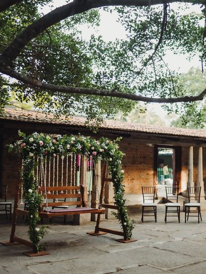 A rustic wooden swing decorated with green foliage and flowers, blending perfectly with the surrounding nature.