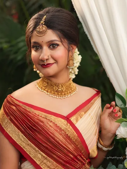 A close-up portrait with a confident and engaging look. The off-shoulder drape of the saree adds a modern touch to the traditional attire.