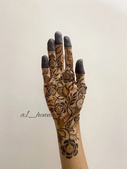 The same floral vine design with the henna paste fully applied, including the traditional dark fingertips.
