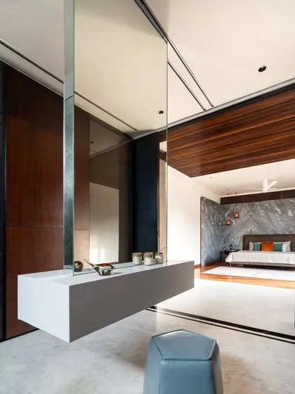 This suspended vanity with a wrap-around mirror creates an ethereal, spacious feel in the dressing room. The design plays with levitation and reflection, blurring boundaries between the dressing area and the master bedroom beyond.