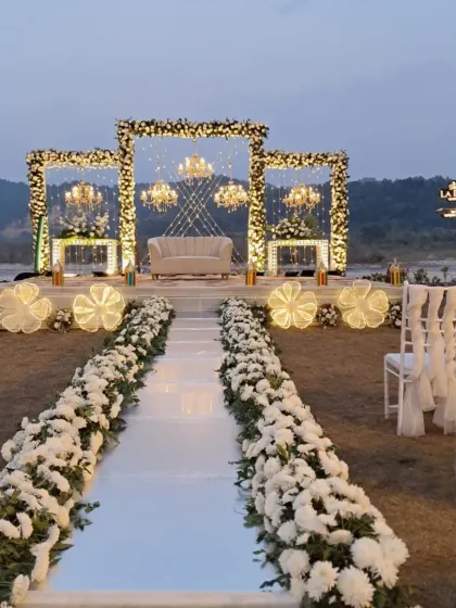We planned this elegant wedding ceremony by the river in Jim Corbett National Park. The decor features a clean white and green floral theme with a stunning backdrop, showing how we blend luxury with natural beauty.
