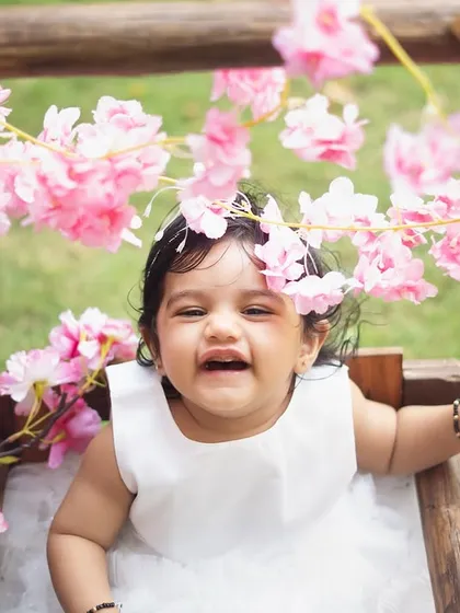 A close-up of the birthday girl, surrounded by pink blossoms. The natural light of an outdoor setting is so flattering and beautiful.
