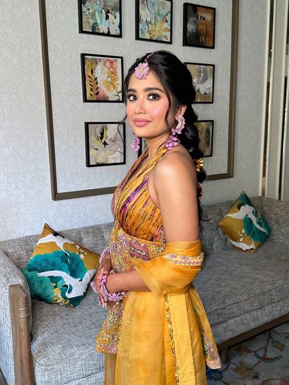 A three-quarter view of the bride, her messy floral braid adding a touch of softness and romance to her Haldi look.
