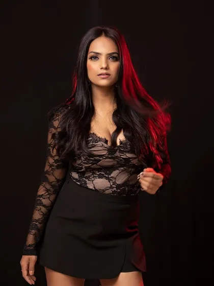 A powerful portrait of a model in a black lace top against a dark background with a hint of red light.