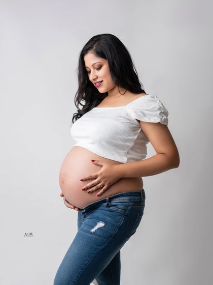A casual and happy maternity portrait. A simple white top and jeans can be the perfect outfit to show off your bump in a relaxed way.