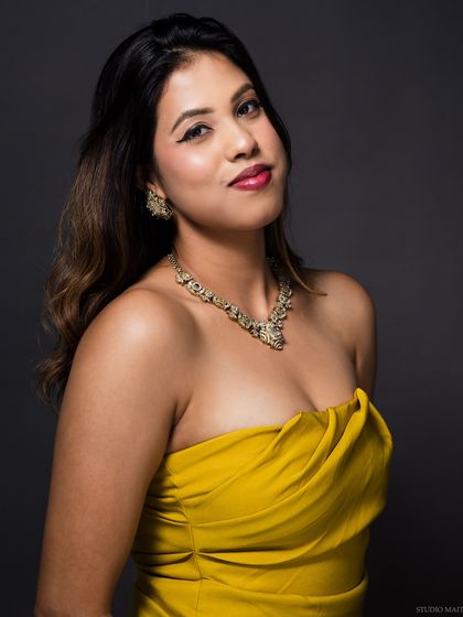 A classic portrait of a model in a yellow strapless top, showcasing her jewellery.