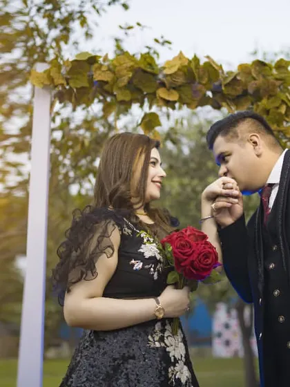 A classic romantic gesture captured beautifully, with the groom kissing the bride's hand under a floral arch.