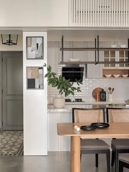 Open-plan living is about creating seamless transitions between spaces. Here, the open kitchen flows into the dining area, anchored by a stunning terrazzo-clad pillar and custom breakfast counter. This design showcases how to create a cohesive and functional home interior, perfect for family life.