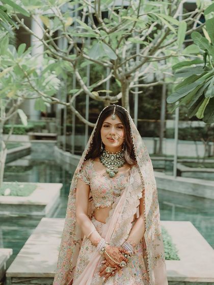 Tanisha posing in a serene garden setting. Her pastel look is a perfect example of modern bridal elegance.