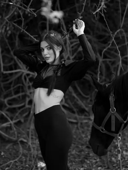A black and white version of a model posing with a horse, which emphasizes the textures and mood of the scene.