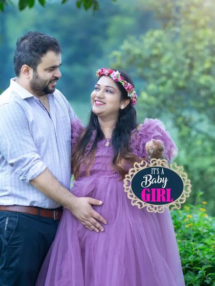 "It's a Baby Girl!" This couple shares their excitement with a cute sign during their maternity shoot, surrounded by the lush greenery of a park.