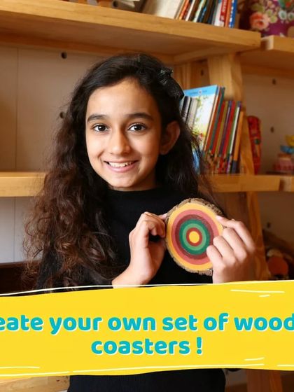 A young artist proudly holds up the wooden coaster she painted. This is a great project that combines art with a useful household item.
