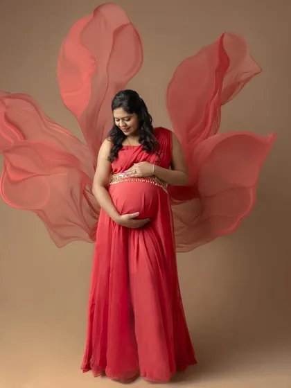 Embracing the goddess within. This portrait showcases the power and beauty of motherhood, using a flowing red gown and soft fabric to create a sense of dreamy elegance for a maternity photoshoot.