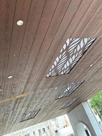 Another angle of the wooden ceiling with leaf-patterned backlit panels, showing the installation in progress with bamboo scaffolding.
